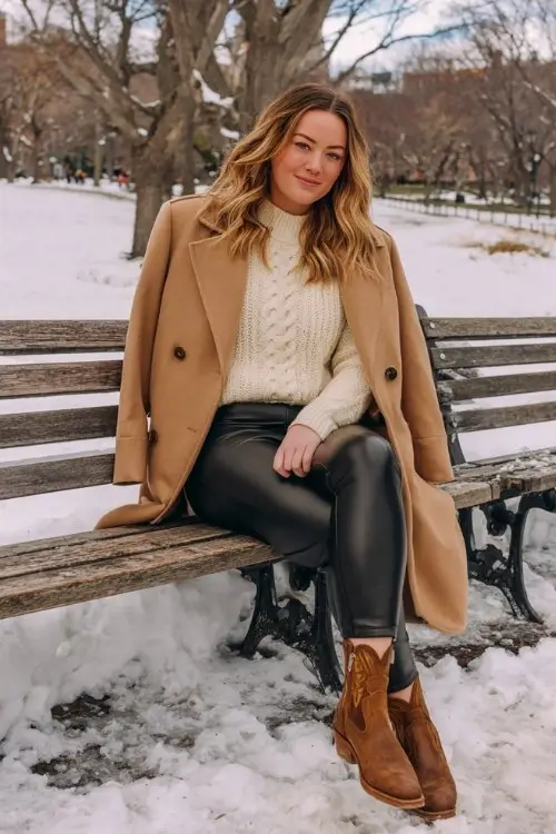 A curvy woman wears black faux leather leggings with suede black cowboy boots