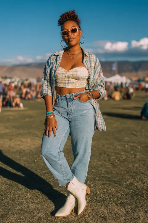 A curvy woman wears white cowboy boots with straight-leg vintage wash jeans, a cropped corset-style top and lightweight plaid shirt worn open
