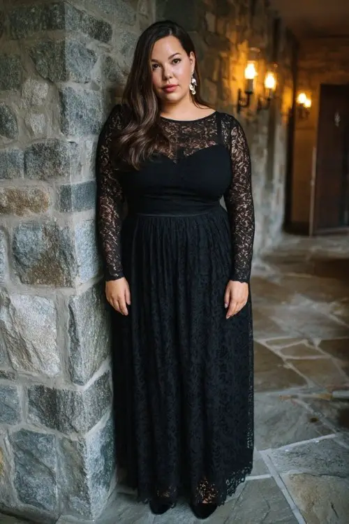 A plus-size woman wears a long-sleeve black lace gown with a modest illusion neckline, fitted bodice, and flared skirt