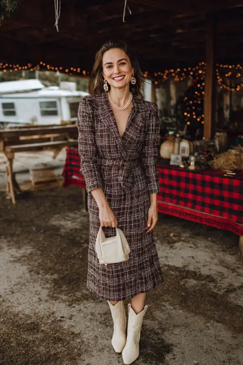 A woman over 30 wears a festive plaid midi dress with refined tailoring, paired with cream cowboy boots and pearl accessories