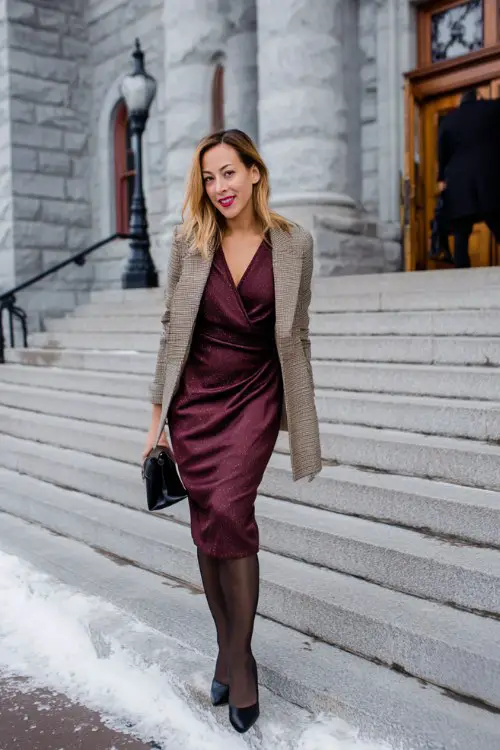 A woman over 40 wears a burgundy wrap-style midi dress with long sleeves and a subtle shimmer
