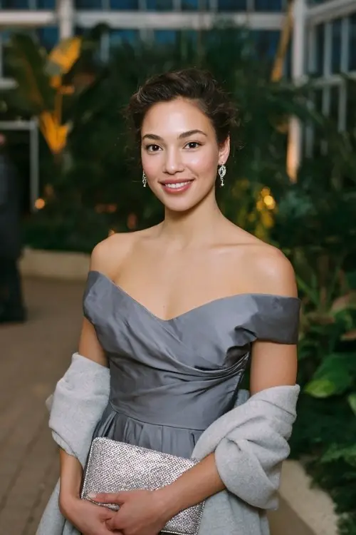 A woman wears a steel-grey taffeta gown with off-shoulder sleeves and side slit, styled with a silver-threaded clutch, a light grey wool wrap