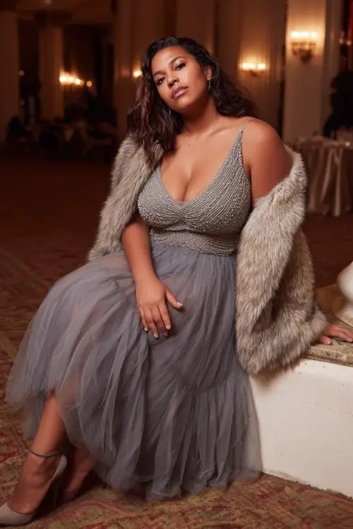 A plus-size woman wears a beaded tulle winter guest dress in soft silver with illusion neckline and flowing skirt