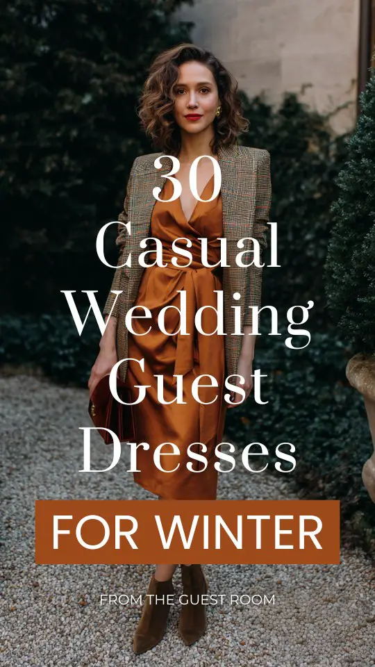 A woman over 30 wears a casual winter wedding guest dress in copper crepe with a structured plaid blazer and low suede ankle boots