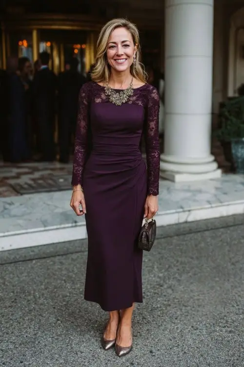 A woman over 40 wears a deep purple column dress with long sleeves and subtle lace insets, paired with metallic pumps and a statement necklace
