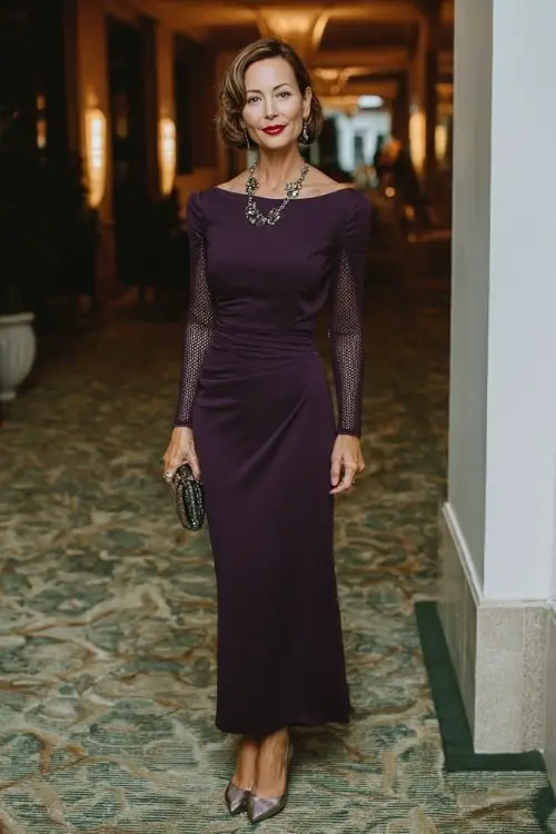 A woman over 40 wears a deep purple column dress with long sleeves and subtle lace insets, paired with metallic pumps and a statement necklace