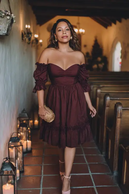 A curvy woman wears a deep wine-colored off-shoulder midi dress with tiered lace ruffles and blush platform heels