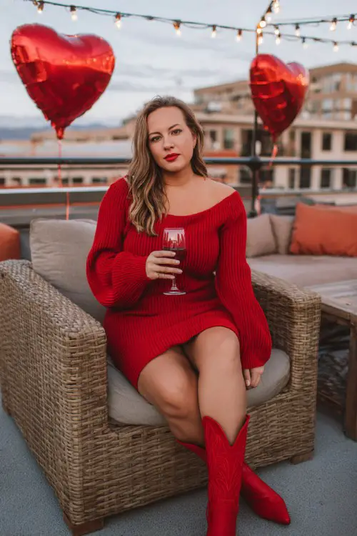 A curvy woman wears a fitted red sweater dress with balloon sleeves and bright red cowboy boots