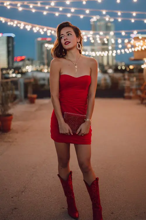 A glam woman in a strapless red bodycon dress and red cowboy boots, holding a red velvet clutch