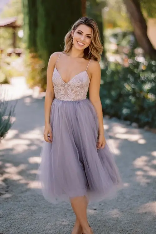 A plus-size woman wears a lavender tulle midi dress with delicate lace bodice and airy skirt movement, paired with block heels