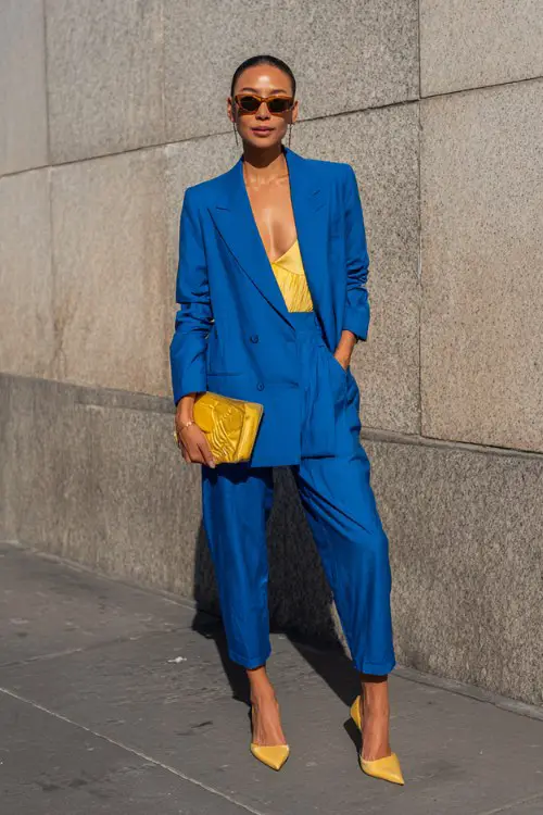A woman over 30 wears a sharply tailored oversized suit in electric cobalt with a structured bralette underneath