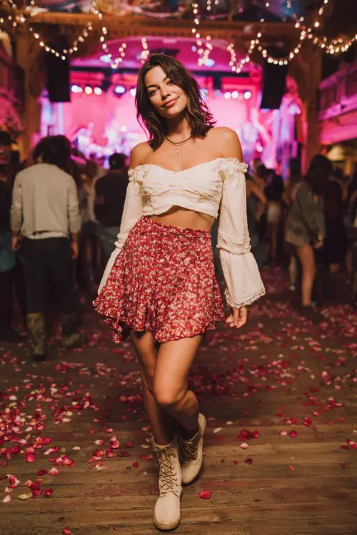 A woman wears a boho red floral skirt with a flowy off-the-shoulder cream blouse and lace-up boots