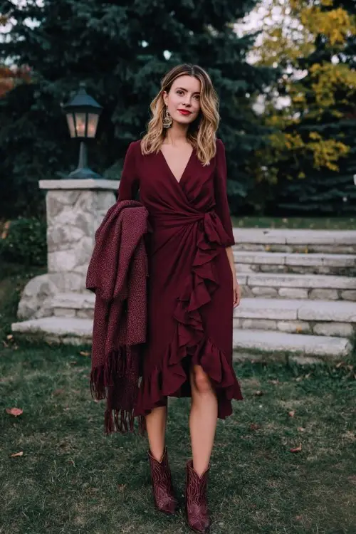 A woman wears a ruffled wrap midi dress in burgundy, styled with heeled cowboy boots and a wool shawl for a romantic winter night