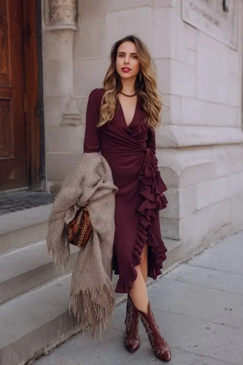 A woman wears a ruffled wrap midi dress in burgundy, styled with heeled cowboy boots and a wool shawl for a romantic winter night