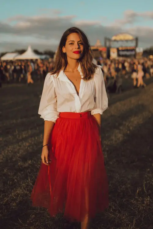 a woman wears a white blouse with a tulle red midi skirt at a country concert