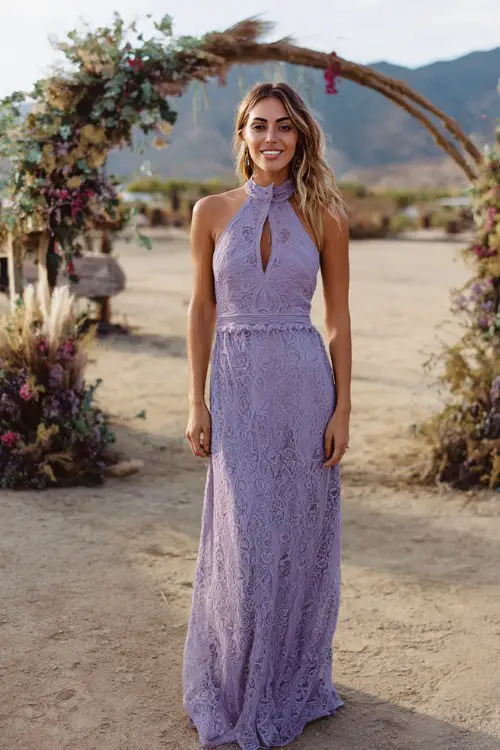 wedding guest wearing a lavender high neck lace gown with delicate embroidery, sleeveless fitted bodice and flowing skirt