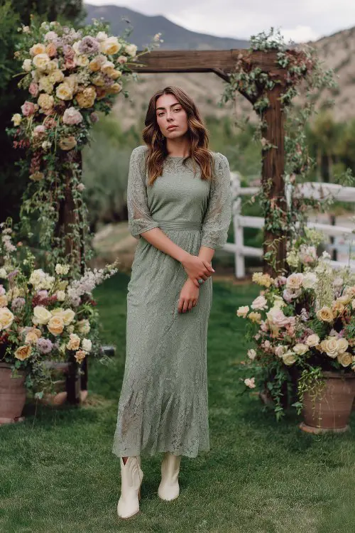 A woman over 30 in a sage green lace maxi dress with illusion sleeves and a soft mermaid flare, styled with cream cowboy boots