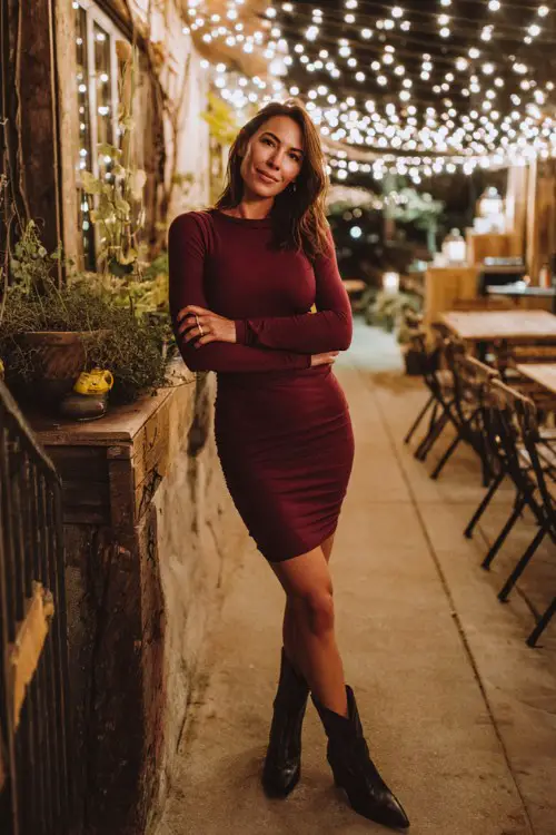 A woman over 30 wears a fitted long-sleeve burgundy dress with sleek black cowboy boots