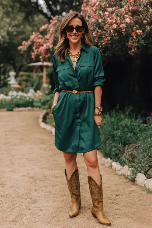 A woman over 40 wears a rich emerald shirt dress with a sharp waistline and rolled sleeves, styled with polished cowboy boots
