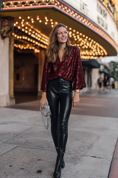 A woman over 40 wears black leather leggings, a sequin-embellished red blouse, ankle boots, and a silver clutch