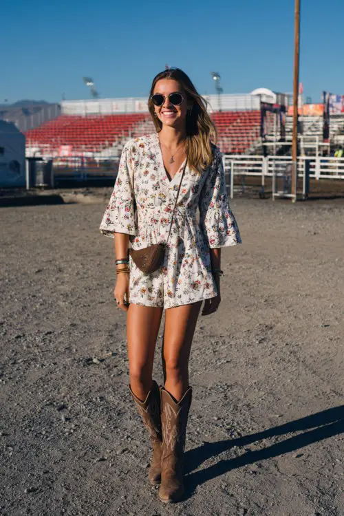 A woman wears a floral-embroidered romper with flared sleeves and brown cowgirl boots