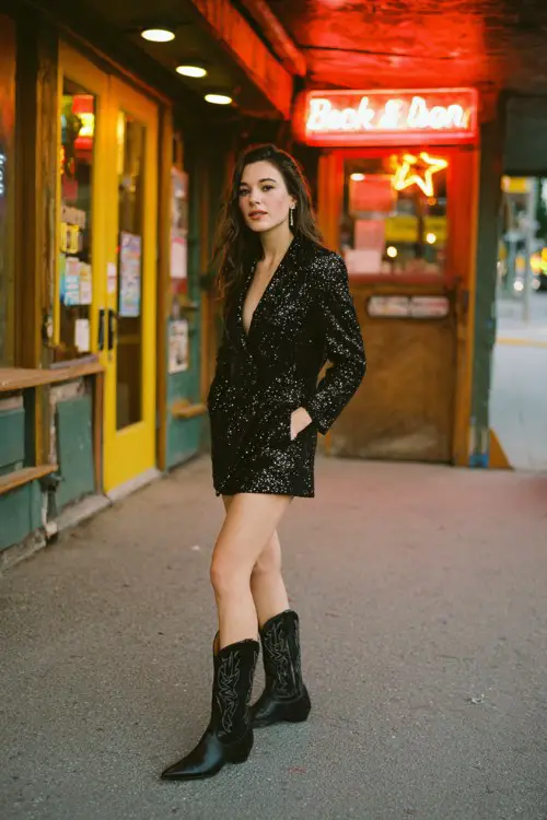A woman wears a sequin black blazer dress with pointed-toe black cowboy boots