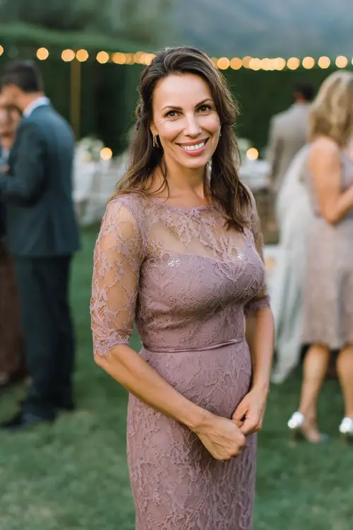petite mature woman in a mauve lace midi dress with sheer sleeves and fitted waist