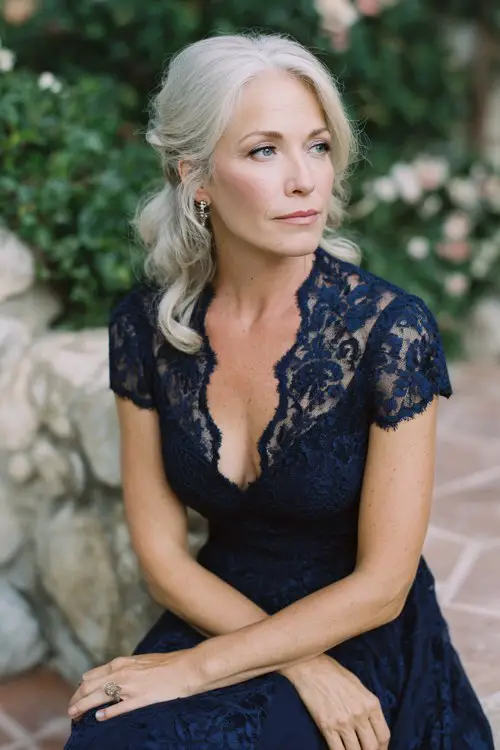 petite older woman in a navy lace gown with v-neckline and short sleeves, flowing skirt, silver hair styled in soft waves