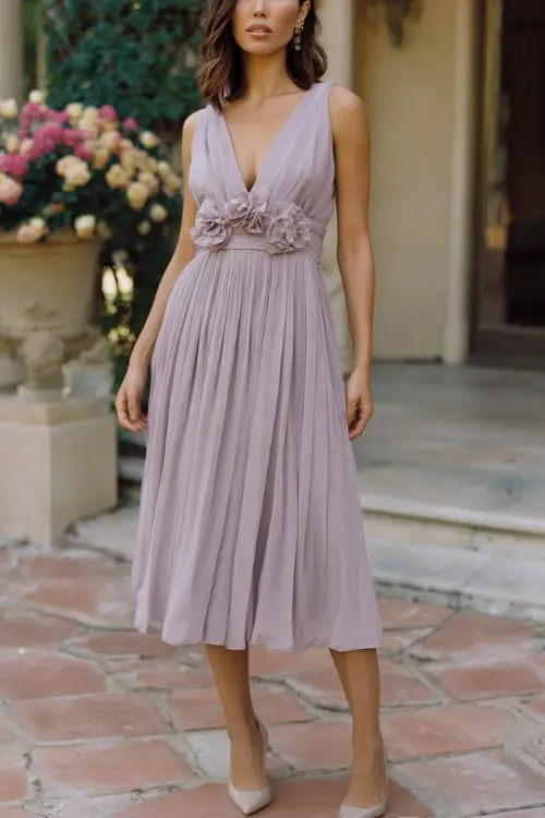 women over 40 wedding guest wearing soft lilac pleated tea-length dress with floral details, neutral heels, defined waistline