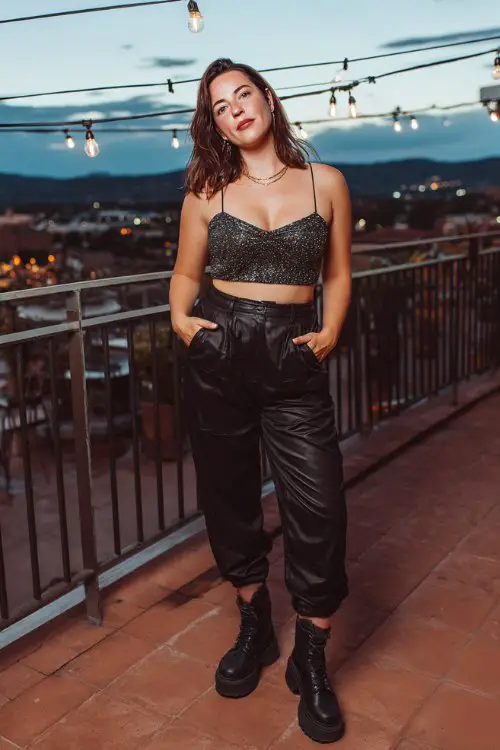 A curvy woman wears black high-waisted pants with a sparkly crop top and chunky platform boots
