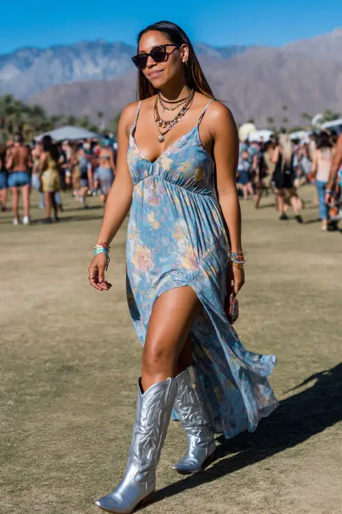 A curvy woman wears metallic silver cowboy boots with a flowing boho maxi dress featuring a high slit and soft pastel prints