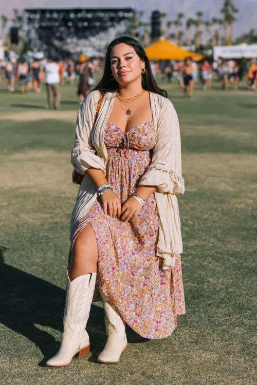A plus-size woman wears cream cowboy boots with a modest floral maxi dress with long sleeves and a cinched waist, layered with a lightweight kimono and delicate jewelry
