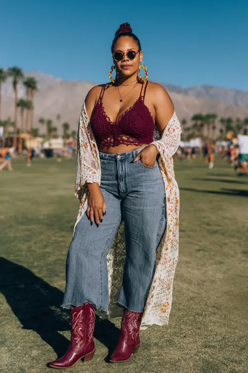 A plus-size woman wears deep red cowboy boots with high-waisted flare jeans and a crochet crop top, layered with a breezy kimono and statement earrings