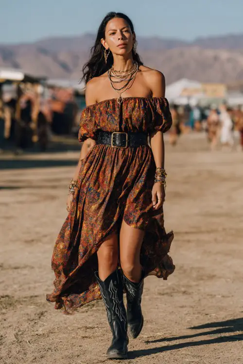 A woman wears black cowboy boots with a breezy off-shoulder maxi dress in earthy tones