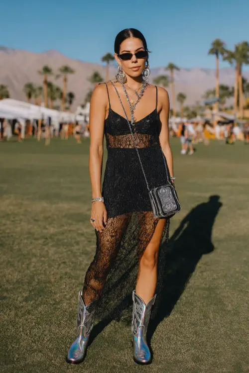 A woman wears holographic cowboy boots with a mesh maxi dress layered over a fitted bodysui