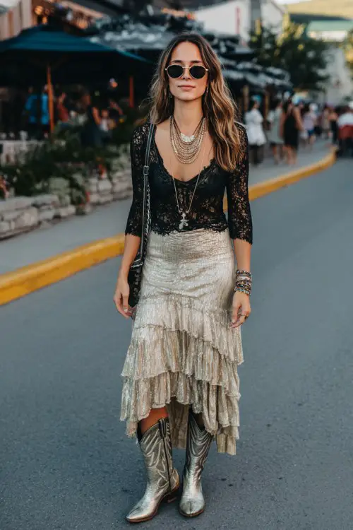 A woman wears metallic cowboy boots with a tiered chiffon maxi skirt and fitted lace top, accessorized with layered necklaces and bold sunglasses