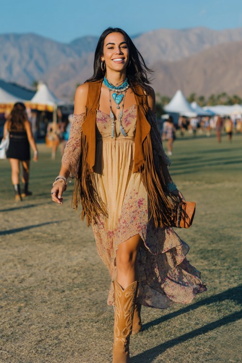 A woman wears tan cowboy boots with a flowing embroidered maxi dress featuring long sleeves and a high neckline