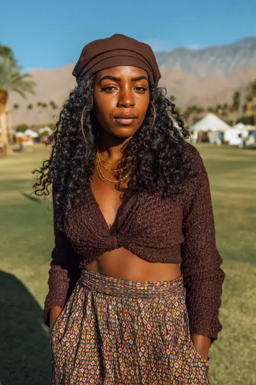 Black woman wears a brown crop top with boho pants and matching hat