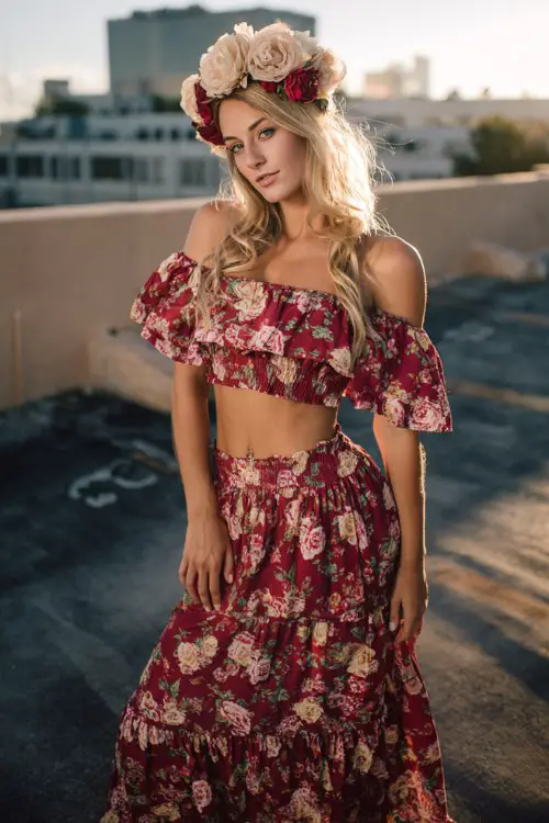 Romantic festival style with tiered floral maxi skirt, off-shoulder blouse, oversized rose flower crown, glowing backlight