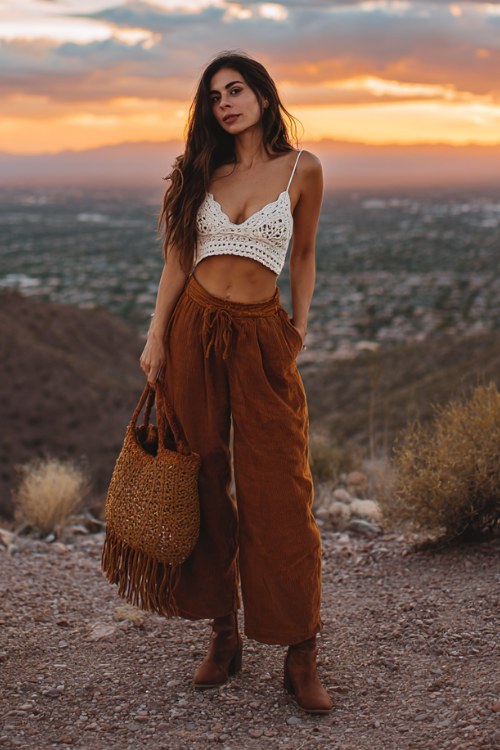 Woman wearing a crochet bralette, flowy boho wide-leg pants, suede ankle boots, fringe bag