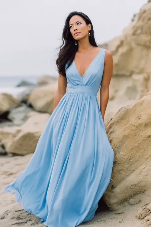a woman wears a flowy chiffon blue wedding guest dress at a beach weddin