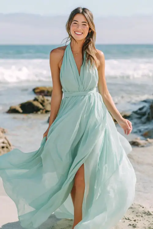 a woman wears a flowy chiffon mint wedding guest dress at a beach wedding