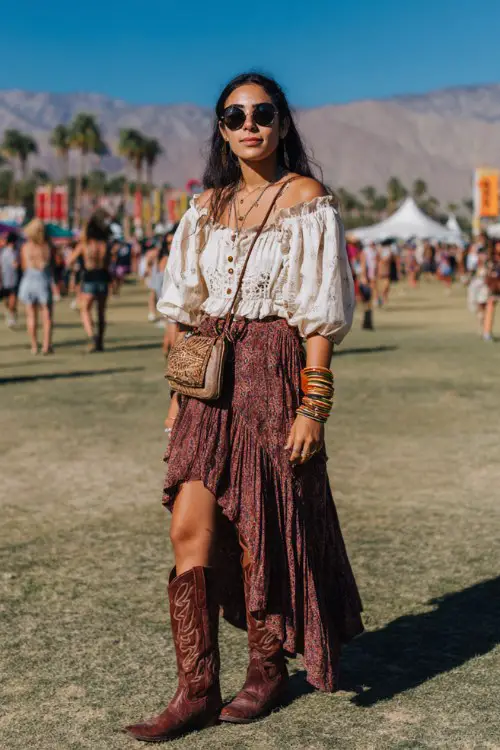 a woman wears brown cowboy boots with a tiered bohemian maxi skirt and a loose embroidered blouse with billowy sleeves