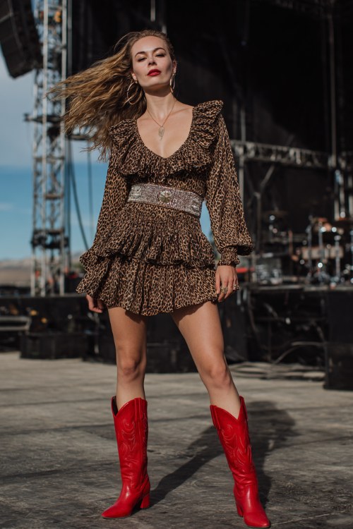 woman wearing a dramatic leopard print ruffled mini dress with a wide embellished belt, voluminous hair blowing in the wind