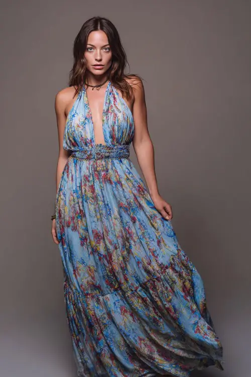 A woman in a flowy halter maxi dress with a low back and flat sandals, styled for a boho-inspired summer bar night, simple studio background