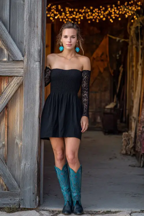 A woman wears a black fit-and-flare dress with lace sleeves, styled with embroidered cowboy boots and turquoise earrings, posing beside rustic barn doors draped with fairy lights