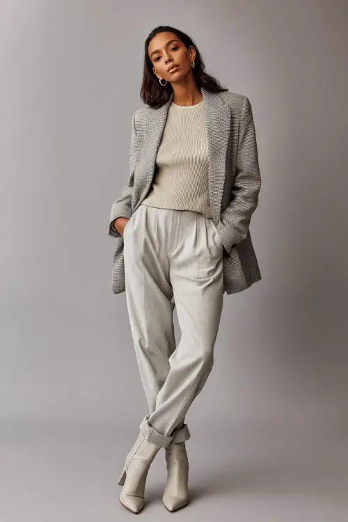 A woman wearing a soft gray tailored blazer over a neutral knit top and straight-leg trousers, styled with pointed ankle boots 