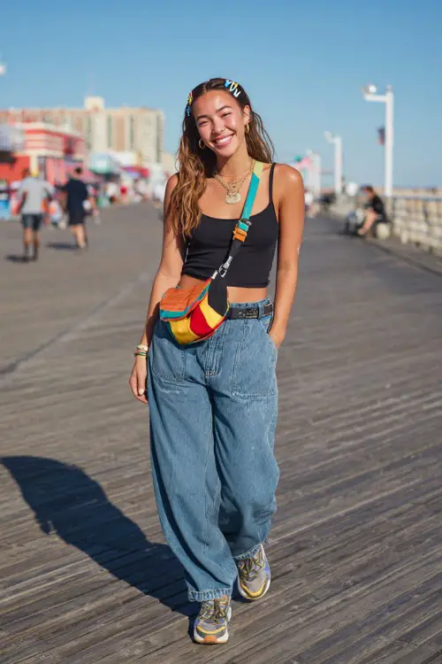 confident woman wearing a fitted tank top with low-rise flare jeans and platform sneakers, accessorized with a colorful shoulder bag and hair clips
