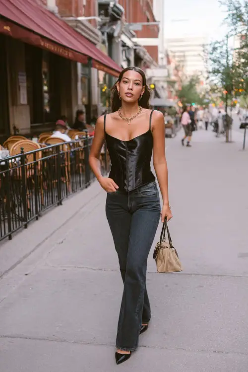 fashionable woman wearing a satin corset top with low-rise bootcut jeans and pointed-toe heels, accessorized with a baguette bag and layered necklaces, chic Y2K outfit with corset