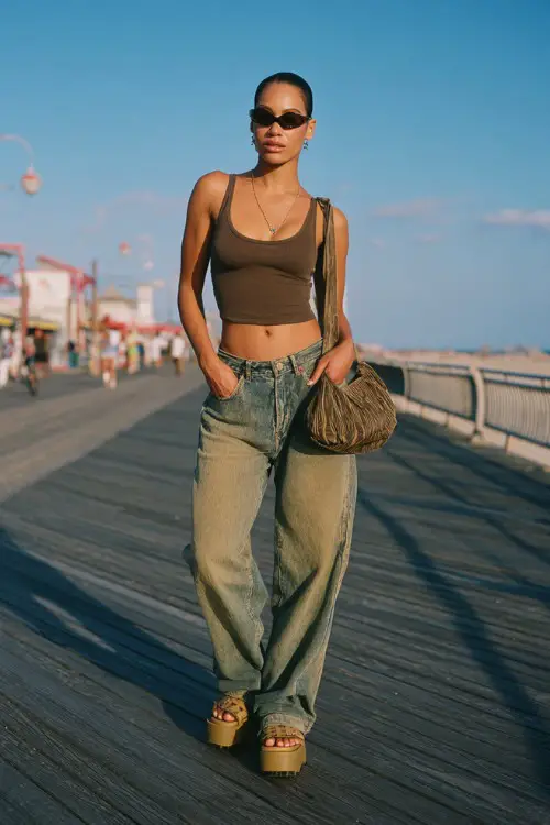 trendy woman wearing a fitted tank top with low-rise baggy jeans and platform sandals, accessorized with tinted sunglasses and a shoulder bag, relaxed early 2000s outfit with baggy jeans